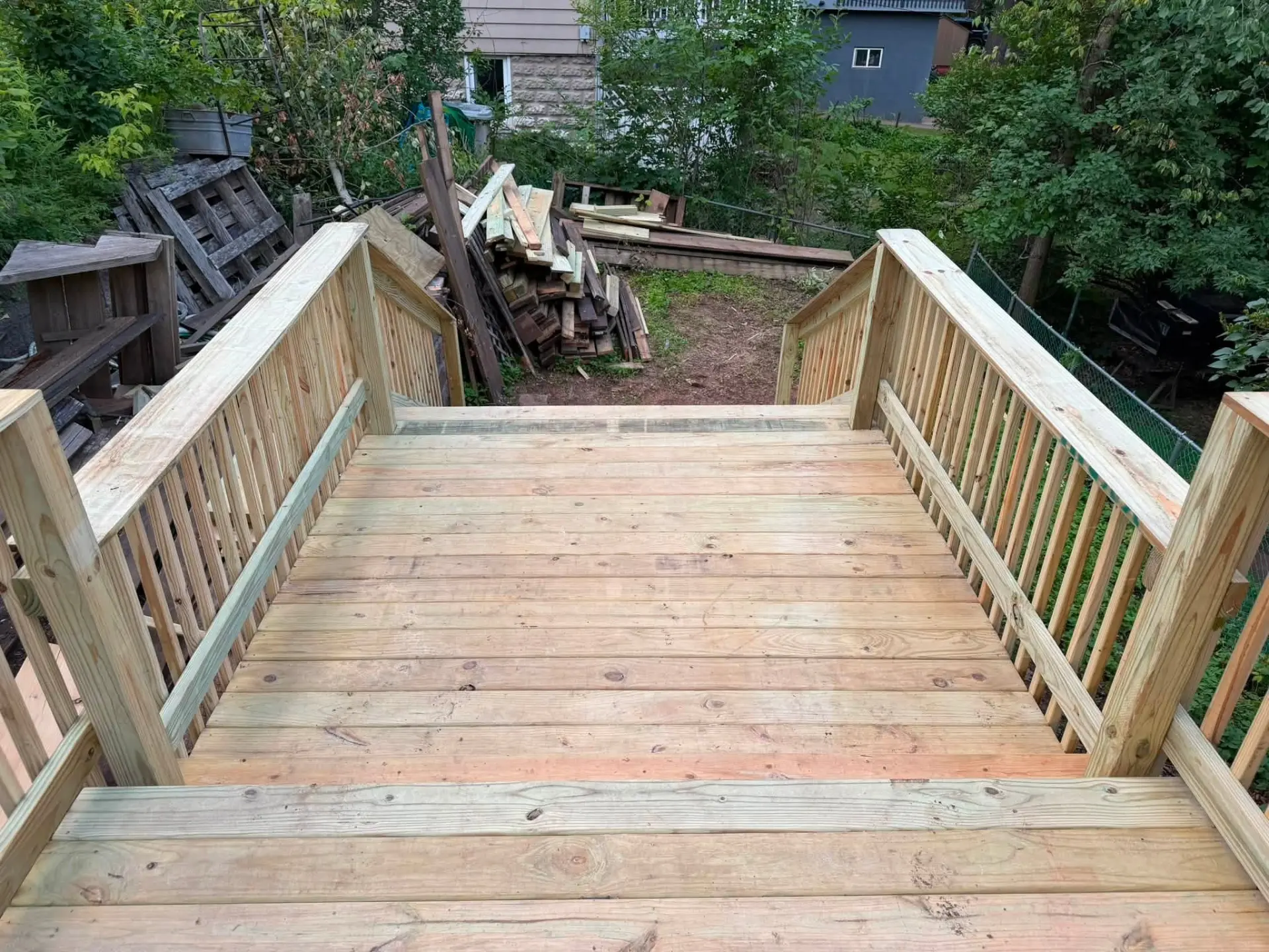 Wooden deck stairs with railings leading down to a backyard